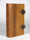Anonym Non Book – Faux Book – Reliquiar aus Holz in Buchform. Von außen betrachtet ein Holzobjekt in Buchform mit Deckeln, Messingschließen und -haften, dreiseitigem Rotschnitt und Kapitalbändchen. Aufgeklappt enthüllt sich unter Glas ein sorgfältiges gefertigtes Reliquiar auf dessen grünem Seidengrund eine zentrale, ovale, farbige und goldgehöhter Fayence, wohl Maria darstellend, sowie zahlreiche, durch Papierstreifen beschrifteten Reliquien montiert sind. Dazwischen fast flächendeckend zahlreiche, mit Goldschnitt versehene sogenannte „Paperolles“, die florale Ornamente und ein Herz formen.